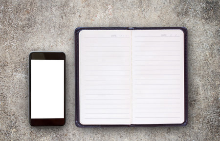 Mobile phone or smartphone with white screen and blank notebooks on the cement floor. Copy space for...