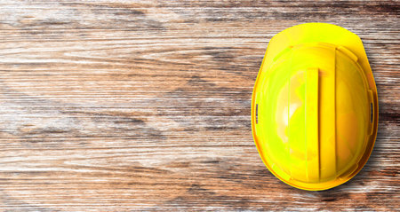Top view of yellow safety helmet hat in the project at construction site building on wood table background. helmet for workman as engineer worker. concept safety firstの写真素材