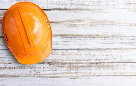 Studio shot. Top view orange safety helmets on white wood table background.helmet for workman as engineer worker. concept safety first.の写真素材