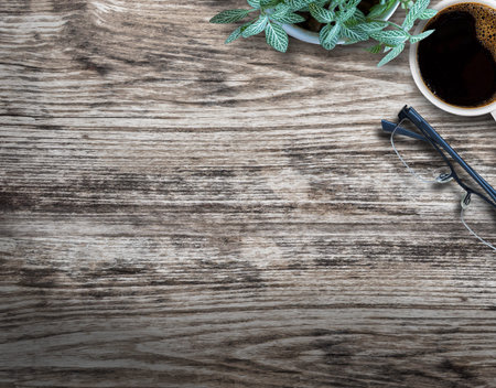 Top view wood table with flower,glasses and cup of coffee on wood background in office workplace.