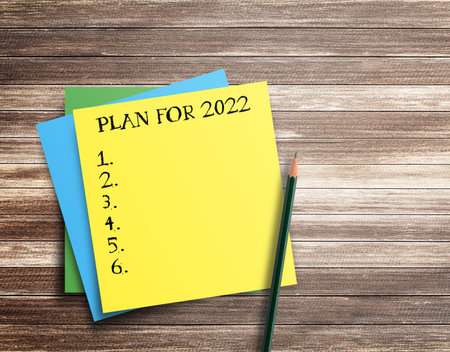 Writing note showing plan for 2022 on wood table background. top view with copy space.Goals ideas...