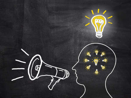 Knowledge and ideas concept sharing with human head shape and megaphone on blackboardの写真素材