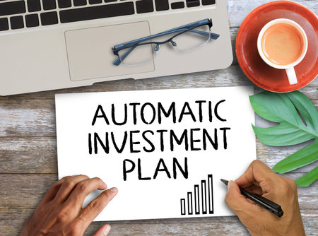 Automatic investment plan letters written on white paper and cup of coffee on wooden table...