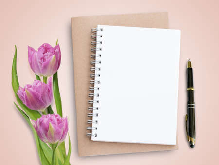 Top view with pink tulips and notebook on pink background. Business concept.の写真素材