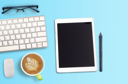 Top view Minmal workspace with glasses, keyboard and coffee cup copy space on blue background. flat...