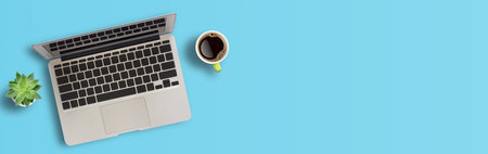 Laptop computer from above with coffee and flower on blue background. Business and marketing concept...