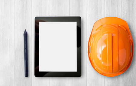 Engineer safety helmet and tablet overhead view. Construction of brown wooden texture background space for designの写真素材