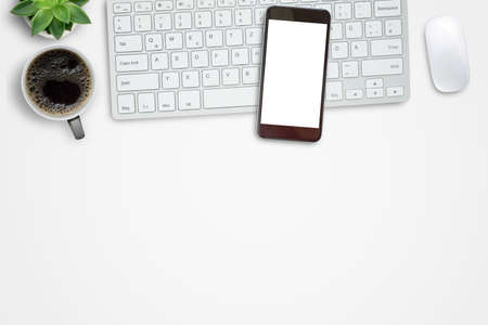 Smartphone,mini keyboard,mouse and hot coffee on white office desk background. Top view with copy space for designの写真素材