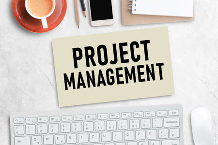 Project Management Text on Office Desk with notebook ,keyboard  and smartphone,coffee,pencil on white marble office desk background. Top view with copy spaceの写真素材