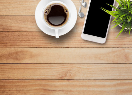 Top view Smart phone and earphone with cup of coffee on old wooden background with copy space.の写真素材
