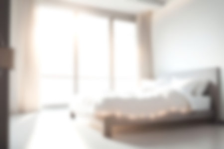 Blur modern bedroom at home with morning soft sunlight at big window for background usage. blur interior background concept. white, bright tone.の写真素材