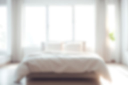 Blur modern bedroom at home with morning soft sunlight at big window for background usage. blur interior background concept. white, bright tone.の写真素材