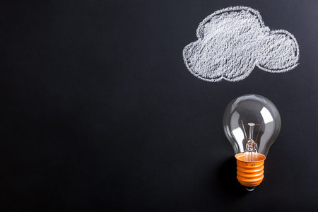 Light bulb with cloud drawn on chalkboard, concept of cloud computing