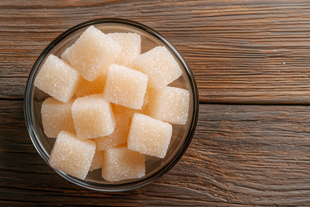 Glass bowl with sugar cubes on wooden table, top view.の写真素材