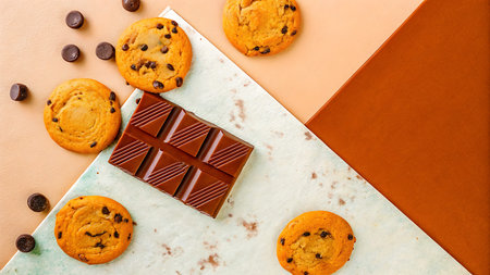 Chocolate chip cookies and chocolate bar on a white and orange background.の写真素材