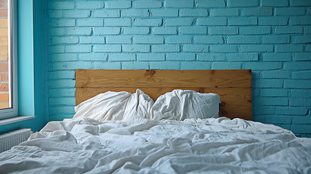 Bed in a room with a blue brick wall and a wooden bedside tableの写真素材