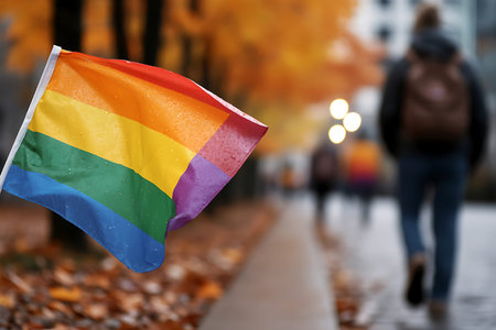 Rainbow flag on the background of blurred people walking in the street
