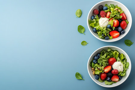 Healthy salad with strawberries, blueberries, rucola and walnuts on blue background. Top view with copy spaceの写真素材