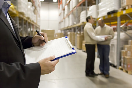 Businessman writing on clipboard in warehouse. This is a freight transportation and distribution warehouse. Industrial and industrial workers conceptの写真素材