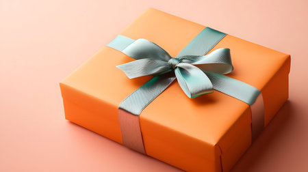 Orange gift box with blue bow on pink background, close up.の写真素材