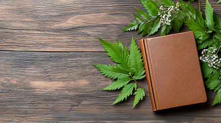 Leather book with green leaves on wooden background. Top view with copy spaceの写真素材