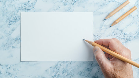 Top view of male hand holding pencil and writing on blank paper sheetの写真素材