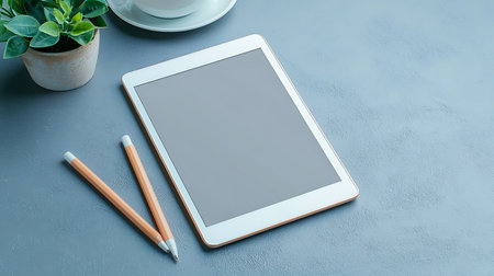 Tablet computer with coffee cup and pencils on blue background.の写真素材
