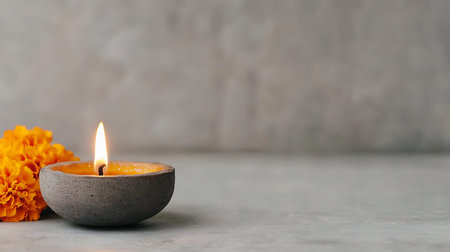 Burning candle with marigold flowers on grey background. Space for text