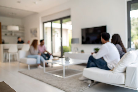 Blurred background of young people sitting in living room and watching tvの写真素材