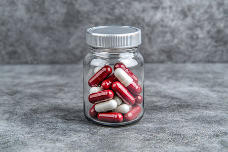 Pills and capsules in a glass jar on a gray concrete backgroundの写真素材