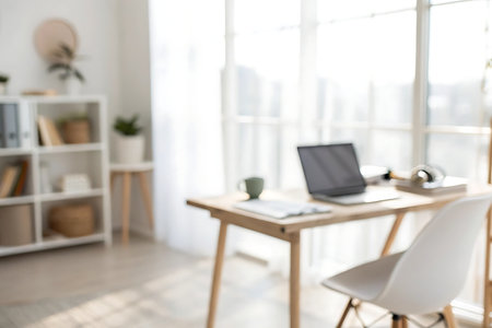 Blurred view of modern workplace with laptop, coffee cup and other itemsの写真素材