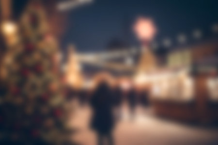 A captivating scene of a Christmas market filled with lights, festive decorations, and joyful people enjoying the holiday spirit during a winter evening.の写真素材