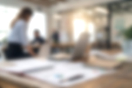 A blurred image showcasing a modern office environment with people collaborating and engaging in...