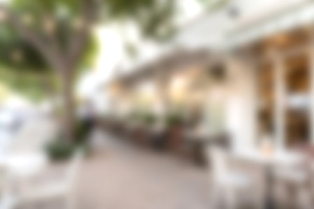 A tranquil outdoor cafe scene featuring inviting seating, ambient lights, and vibrant greenery, perfect for relaxation and social gatherings in an urban setting.の写真素材