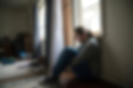 An intimate scene capturing a person sitting quietly in a softly lit room. The natural light filters through a window, creating an atmosphere of reflection and calm.の写真素材