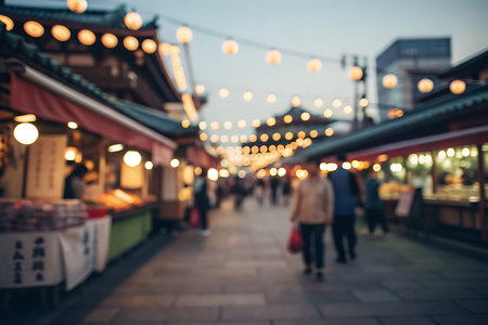 A bustling market scene in the evening, featuring colorful stalls illuminated by beautiful lanterns. The soft focus blur captures the lively atmosphere.の写真素材