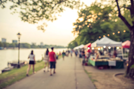 A soft-focus image captures individuals strolling along a scenic riverbank, with market stalls in...