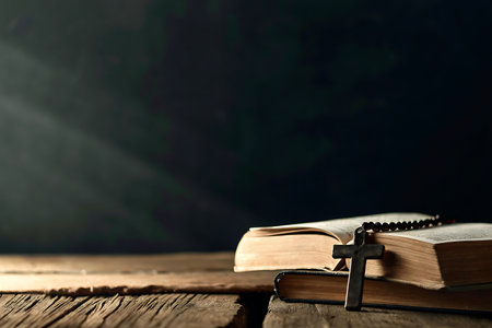A Bible lies open on a wooden surface, accompanied by a rosary, illuminated by soft light, creating a serene atmosphere for reflection and prayer.の写真素材