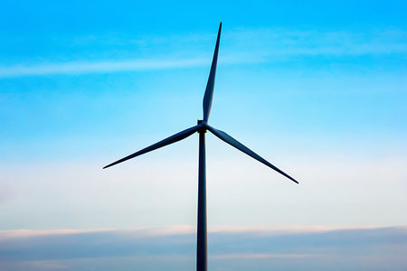 A solitary wind turbine stands against a vibrant blue sky, symbolizing clean energy and...