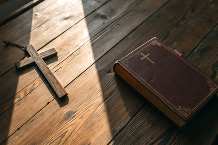 A wooden cross and a leather-bound Bible rest on a rustic table, illuminated by gentle sunlight....