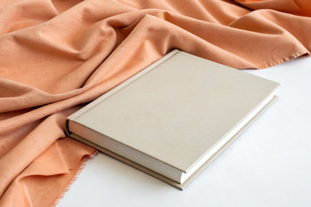 A minimalist book rests elegantly on a soft, warm fabric, creating a cozy aesthetic. Ideal for...