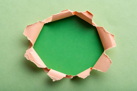 A creatively torn paper frame reveals a vibrant green background, perfect for artful projects or marketing visuals. Ideal for dynamic designs.の写真素材