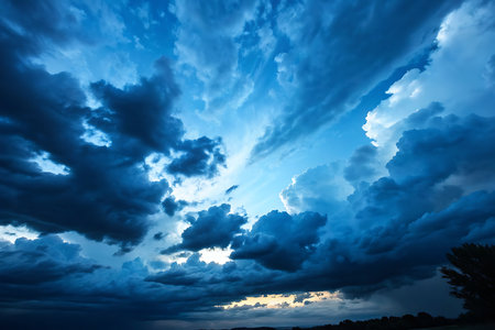 A stunning display of a dramatic cloudy sky at dusk, showcasing rich blue hues and sunlight illuminating the clouds. Perfect for nature-themed projects.の写真素材