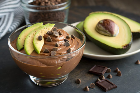 A tempting bowl of creamy chocolate avocado mousse garnished with fresh avocado slices and chocolate...