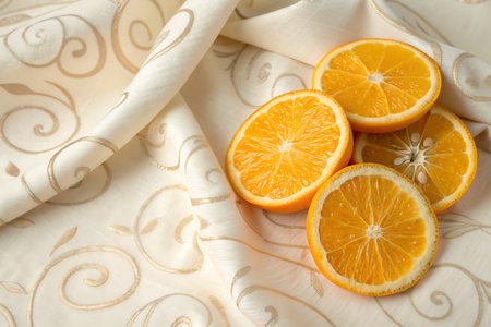 Bright orange fruit slices arranged elegantly on soft, decorative fabric create a vibrant and fresh visual. Ideal for food photography or culinary art.の写真素材