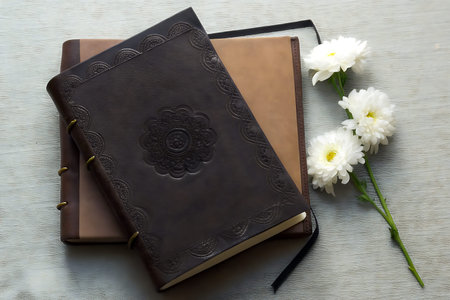 A beautifully arranged leather-bound journal and flowers on a textured surface, ideal for moments of...