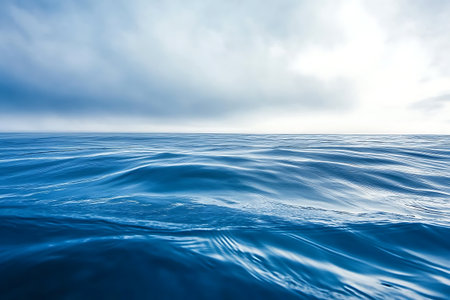 Experience the serene beauty of a calm sea under a cloudy sky. The gentle waves create a tranquil atmosphere, reflecting the soothing blue tones of nature.の写真素材