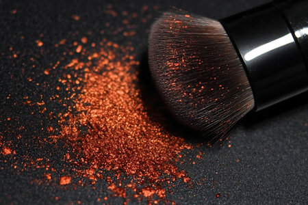 This stunning close-up image features a makeup brush alongside shimmering copper powder against a...
