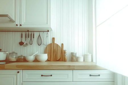 A sunlit kitchen counter featuring wooden boards, white bowls, and various cooking utensils,...