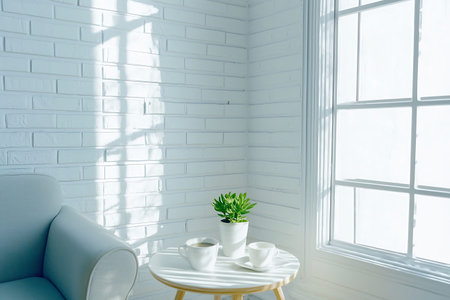 A cozy and bright corner featuring a minimalist design with a small table, plants, and cups....